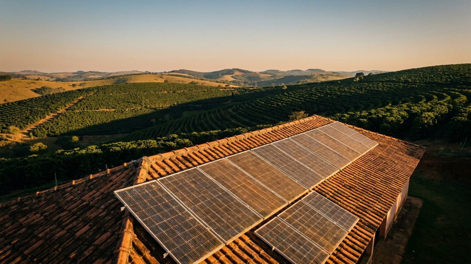 Telhado com placas solares no fim da tarde e morros de café do Sul de Minas ao fundo